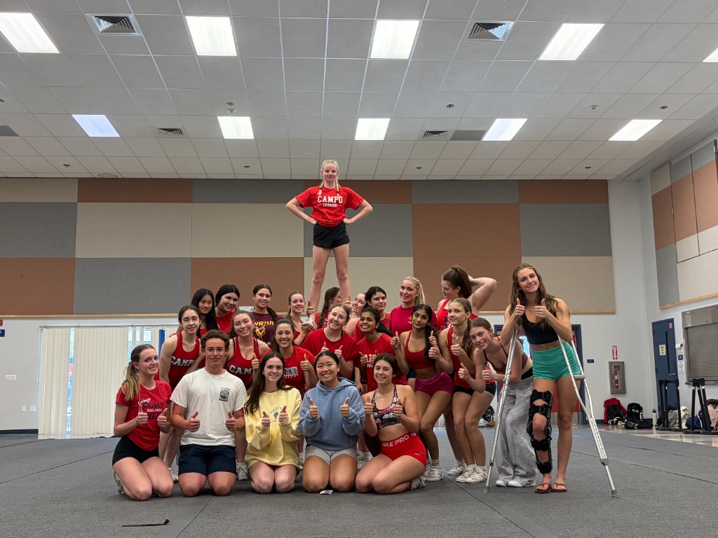 Cheerleading team forming a pyramid in a gym, all smiling
