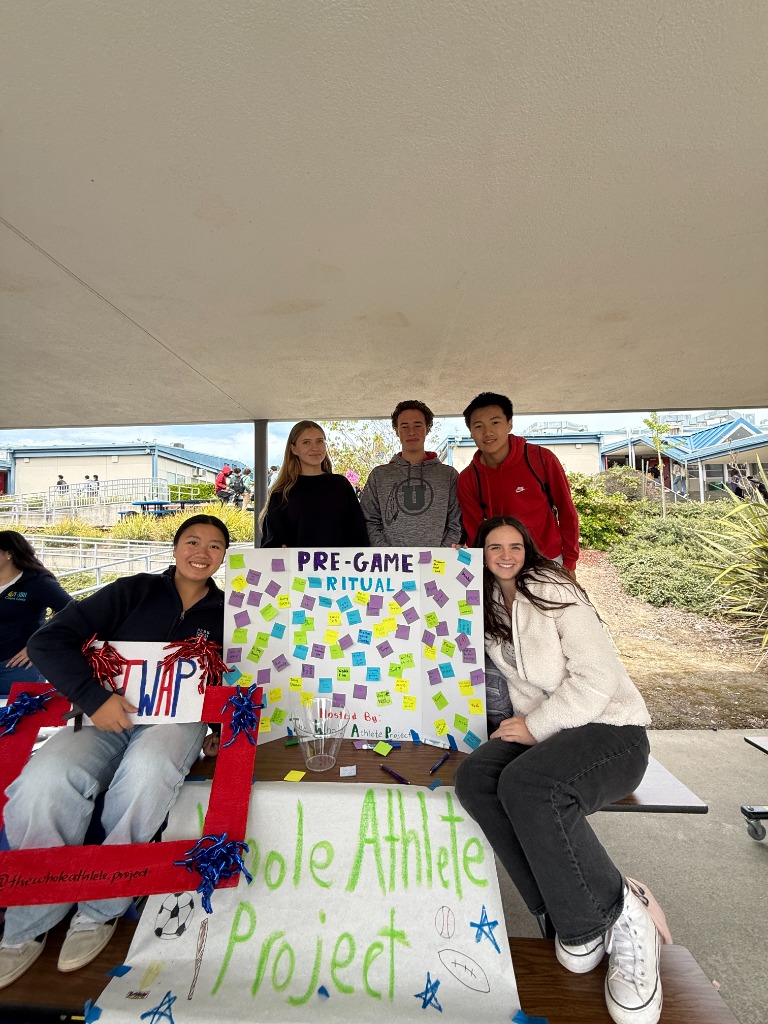 TWAP members at a campus booth with a Pre-Game Ritual poster covered in sticky notes