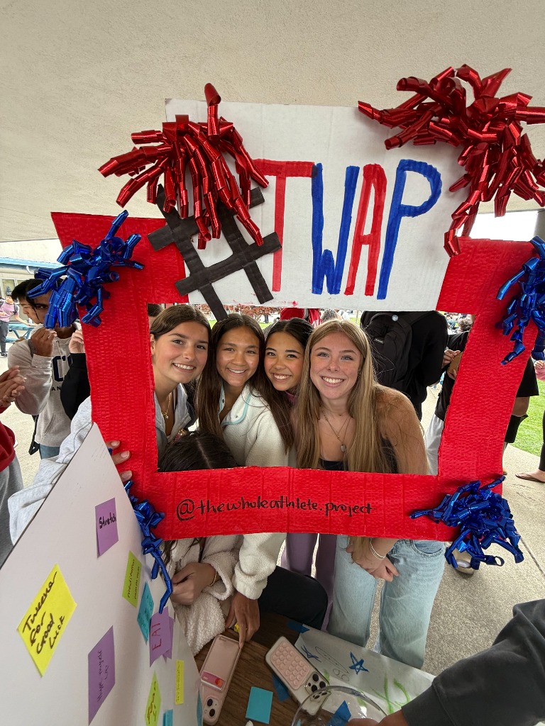 Four female student-athletes posing with a handmade TWAP sign
