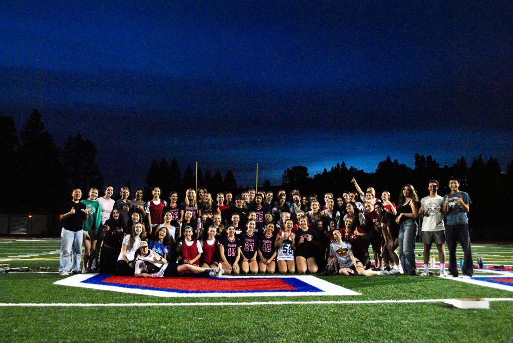 Large group of student-athletes gathered on a football field at night