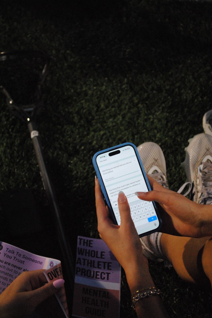Student filling out a TWAP mental health survey on their phone at an outdoor event