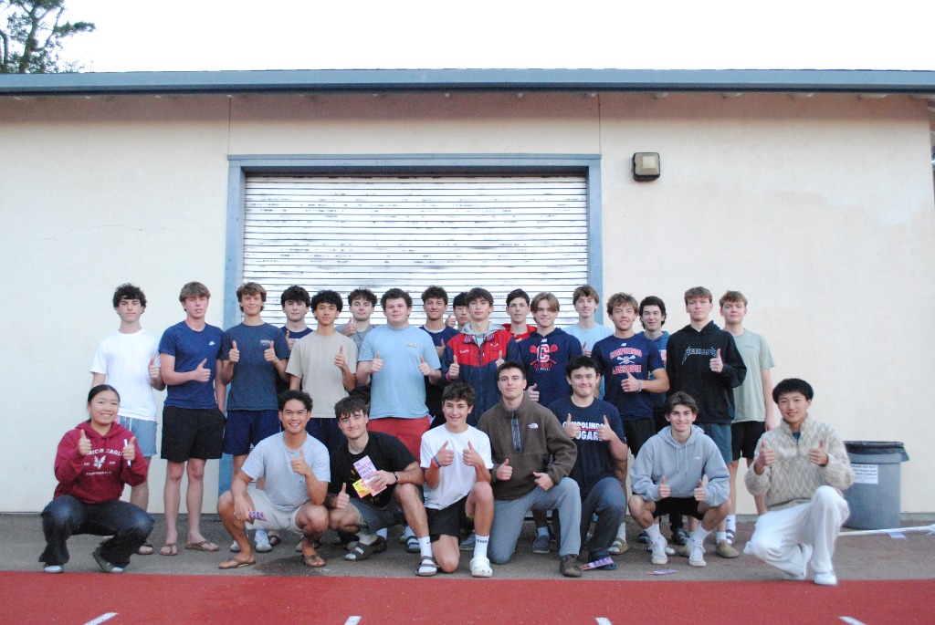 A large group of student-athletes giving thumbs up together on a track